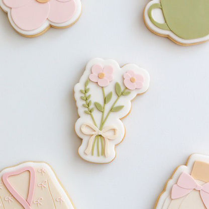 Koekje met een pastel bloemboeket en strik op een lichte ondergrond