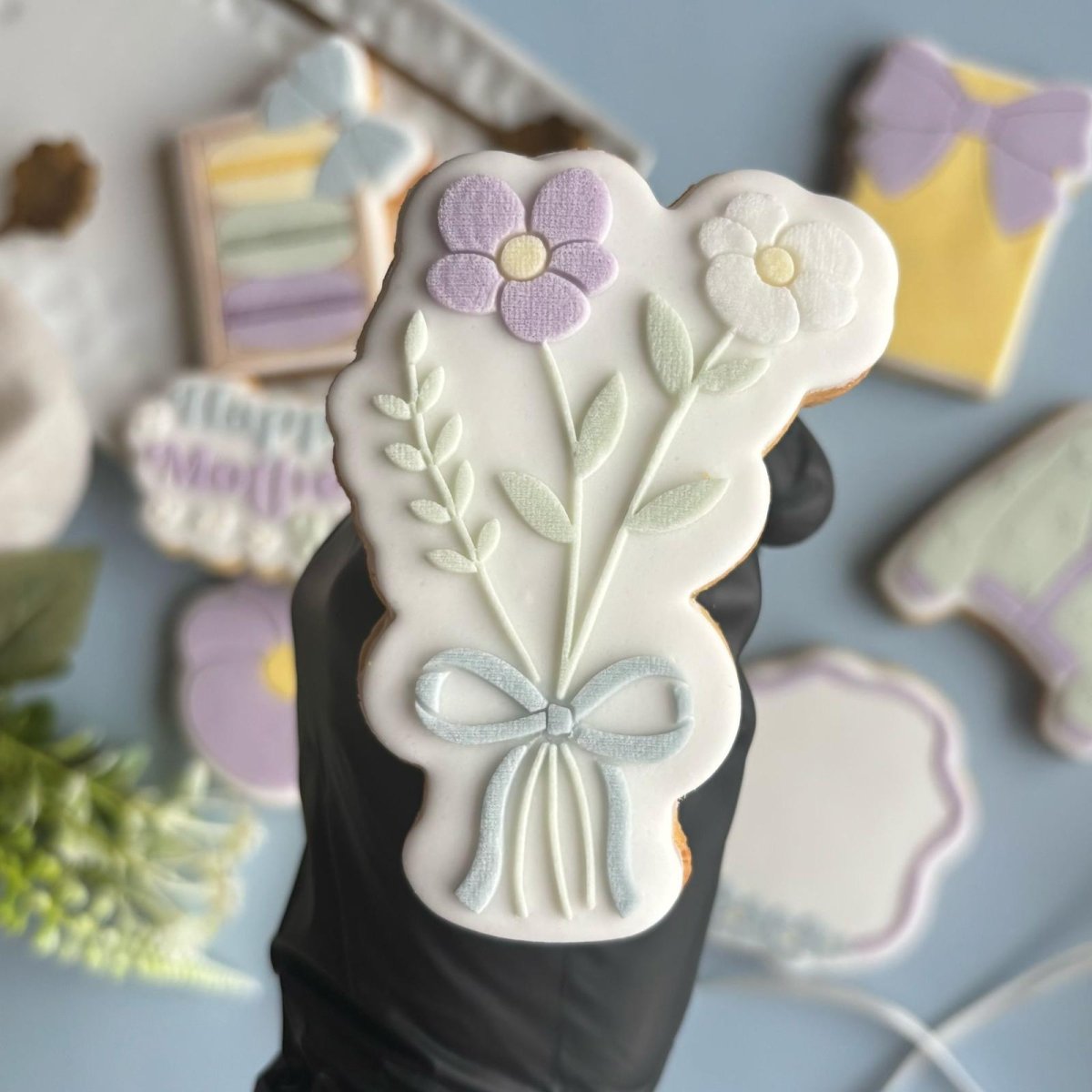 Bloemboeket koekje in de hand, met andere moederdagkoekjes op de achtergrond