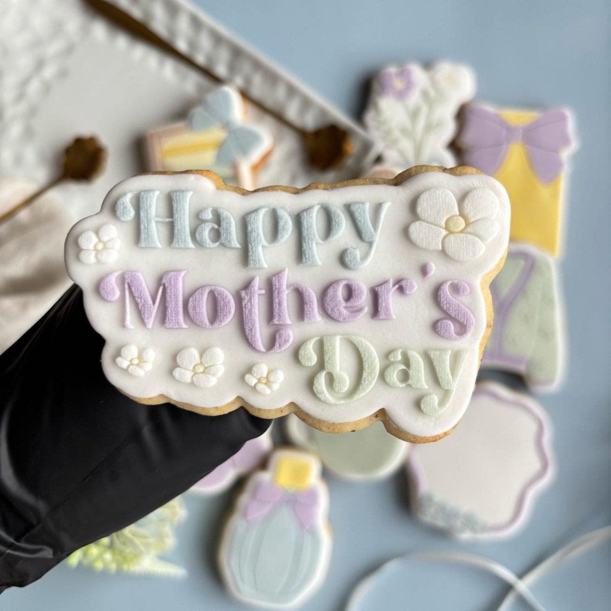 Happy Mother's Day koekje in de hand tussen andere moederdagkoekjes