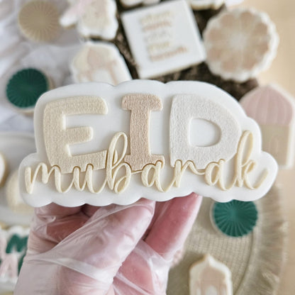 Koekje met EID in grote letters en mubarak in goudkleurige sierletters