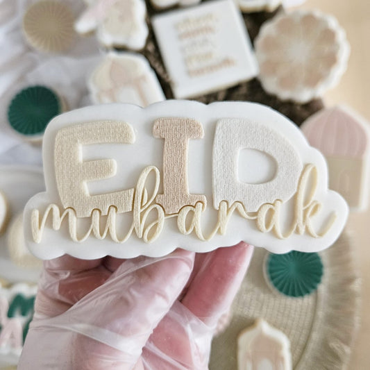 Koekje met EID in grote letters en mubarak in goudkleurige sierletters