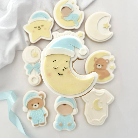 Geel maankoekje met lichtblauw slaapmutsje tussen babykoekjes