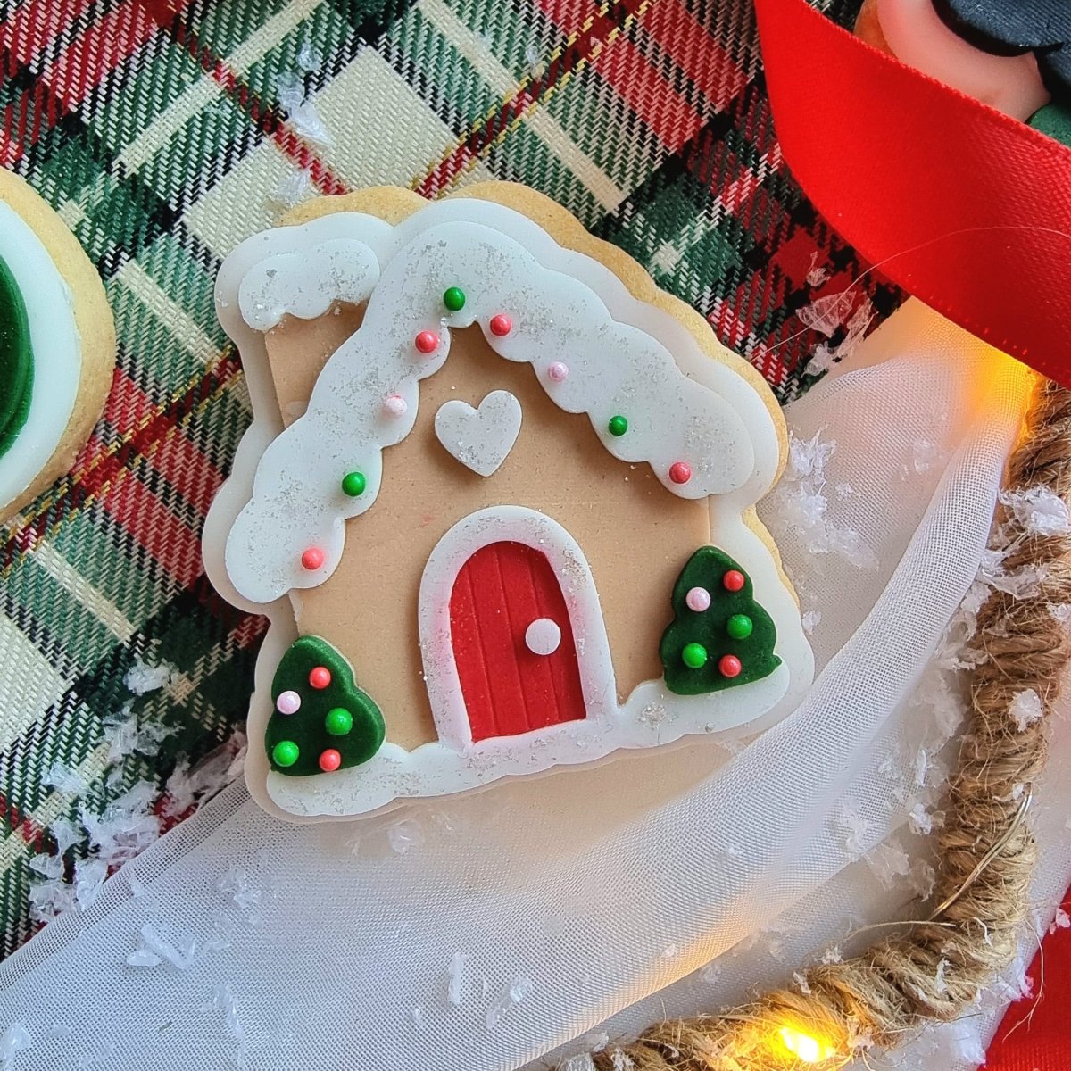 Mini koekje van een peperkoekhuisje met rode deur en twee boompjes